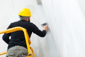 Interior construction, worker plastering gypsum board wall.